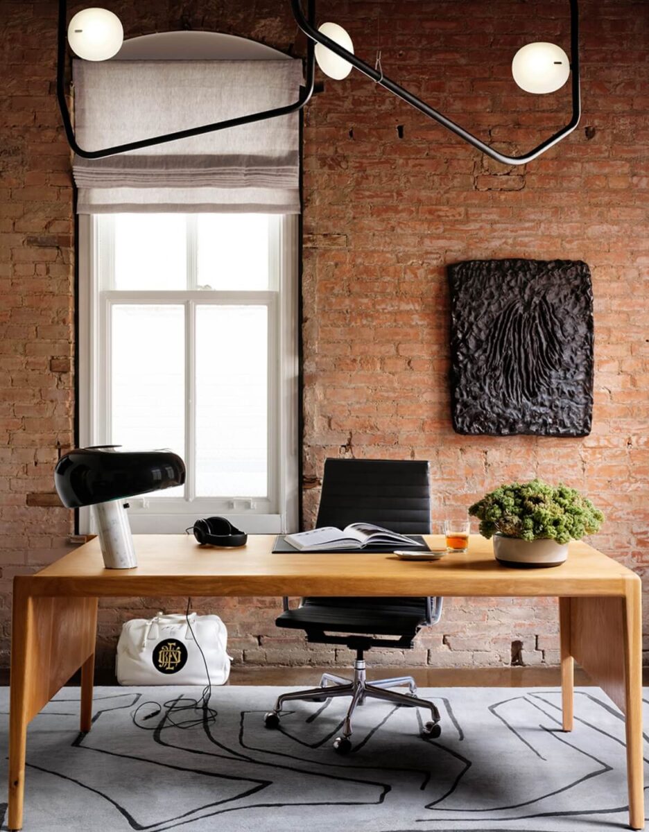 minimalist light-colored wood desk in front of rustic red brick wall