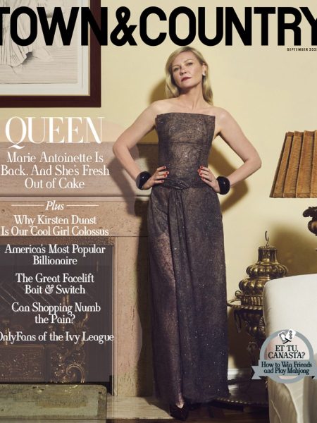 Kirsten Dunst poses in a strapless, floor-length gown with black bracelets, standing indoors next to a gold-trimmed screen. The Town & Country magazine cover headline reads Queen with features about Dunst and lifestyle topics.